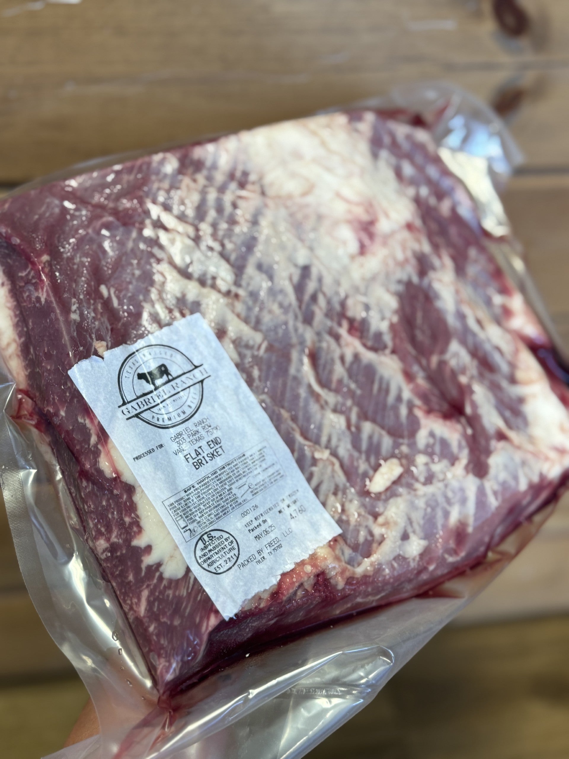 Close-up of hand-packaged chicken cuts with visible farm-raised labels and detailed marbling on organic beef pieces